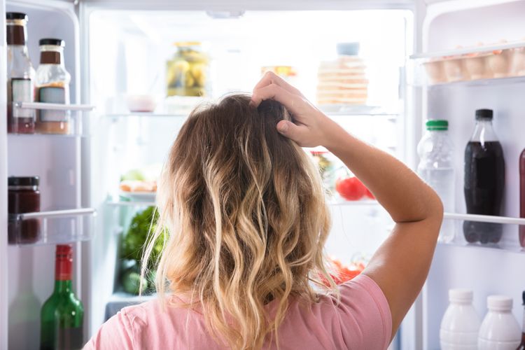 Žena rozmýšľajúca pred otvorenou chladničkou