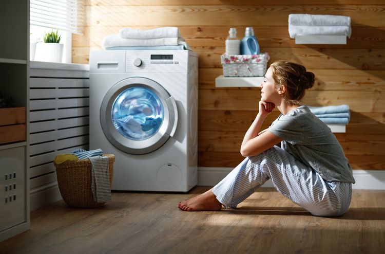 Žena pozerajúca na práčku