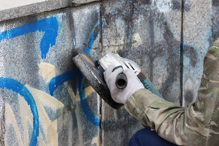 Odstraňovanie grafitov z múru pomocou brúsky