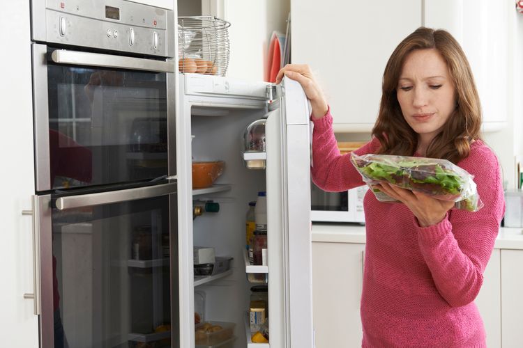 Žena držiaca šalát pred chladničkou